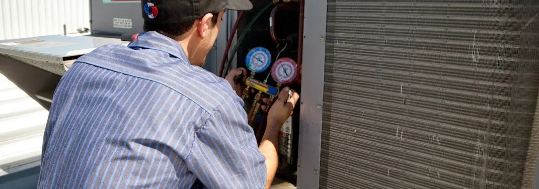 HVAC technician servicing a condenser unit in East Troy
