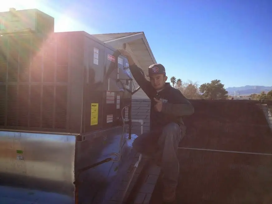 HVAC technician performing AC Tune-Up on a rooftop unit in East Troy